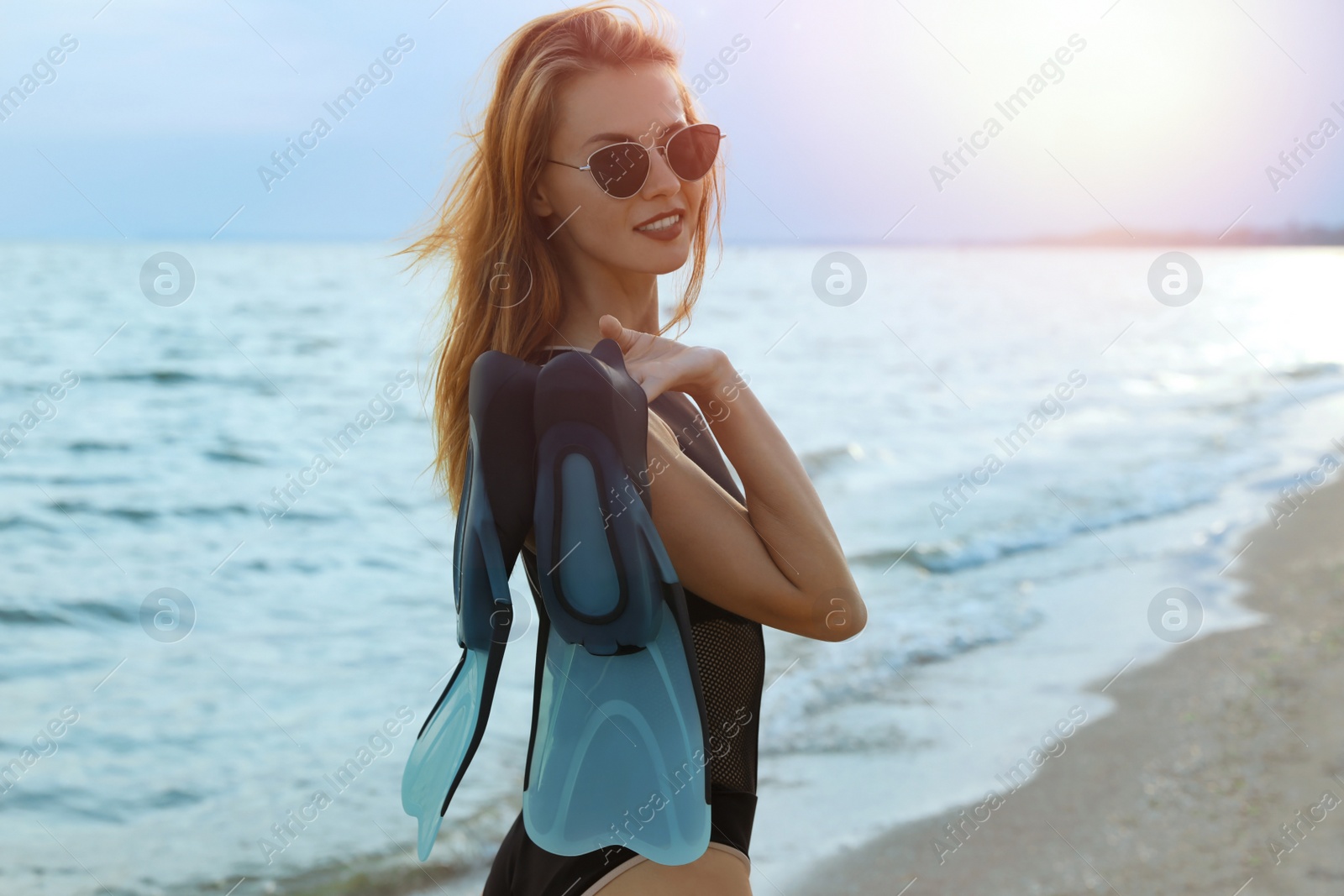 Photo of Happy woman with flippers near sea on beach