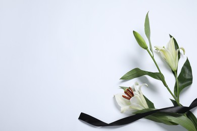 Photo of Beautiful lilies and black ribbon on white background, top view with space for text. Funeral symbol
