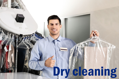 Portrait of happy worker with clothes near counter at dry-cleaner's