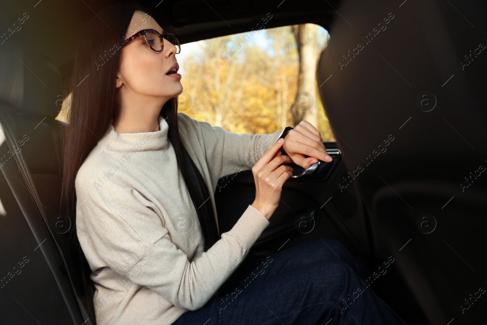 Photo of Emotional woman checking time on watch in car. Being late concept