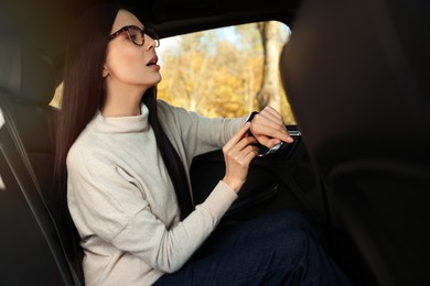 Emotional woman checking time on watch in car. Being late concept