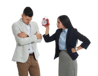 Businesswoman with alarm clock scolding employee for being late on white background