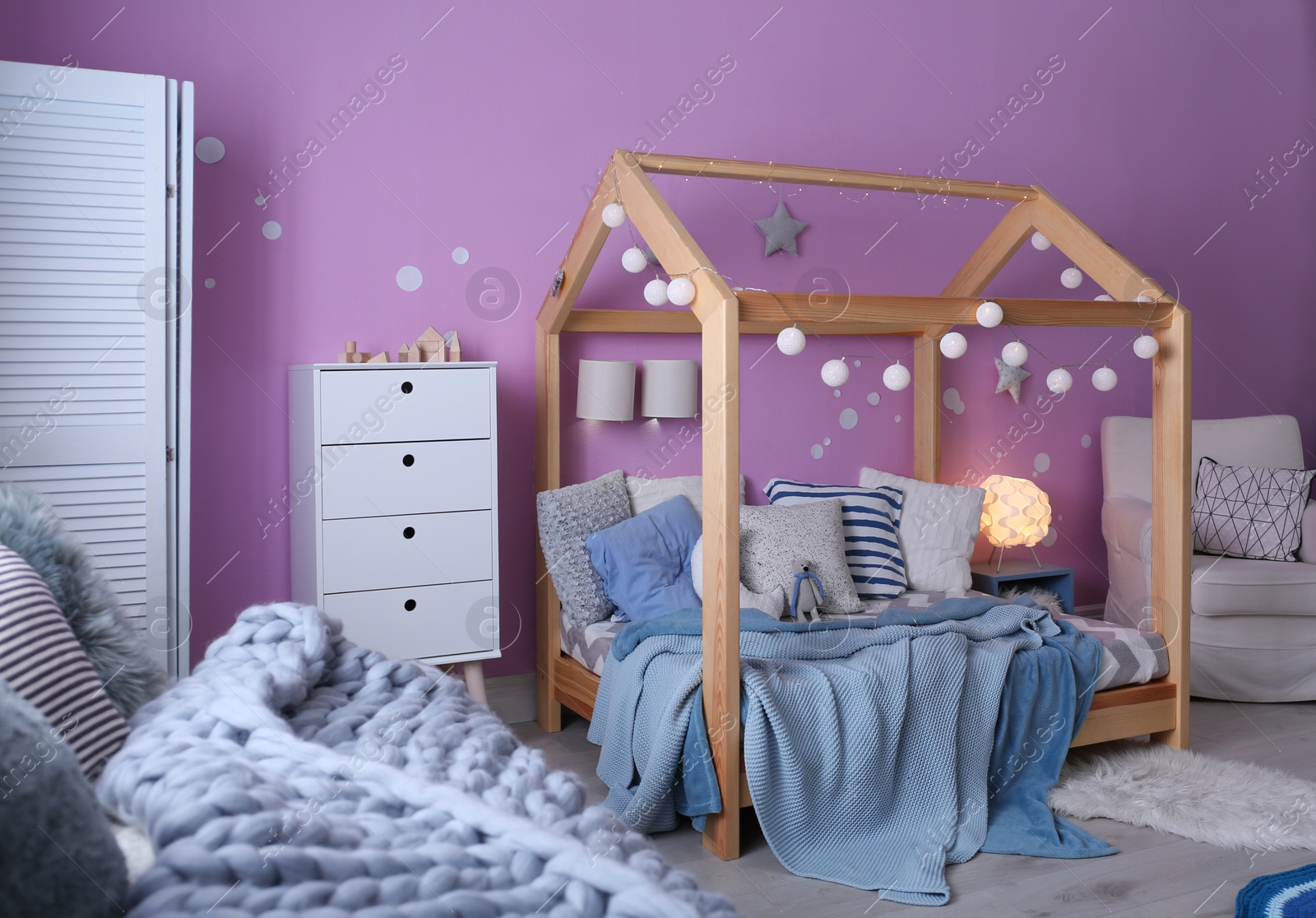 Photo of Child's room interior with comfortable bed and garland