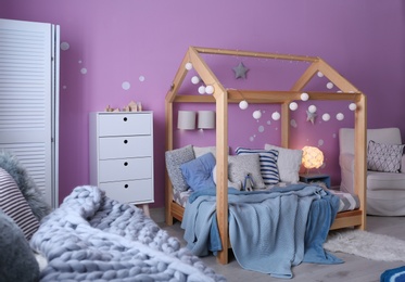 Child's room interior with comfortable bed and garland