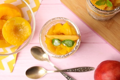 Photo of Tasty peach dessert with yogurt served on pink wooden table, flat lay