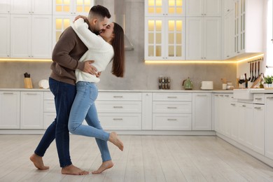 Photo of Affectionate young couple kissing in kitchen. Space for text
