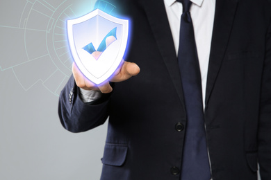 Cyber insurance concept. Man using virtual screen with shield illustration as symbol of protection, closeup