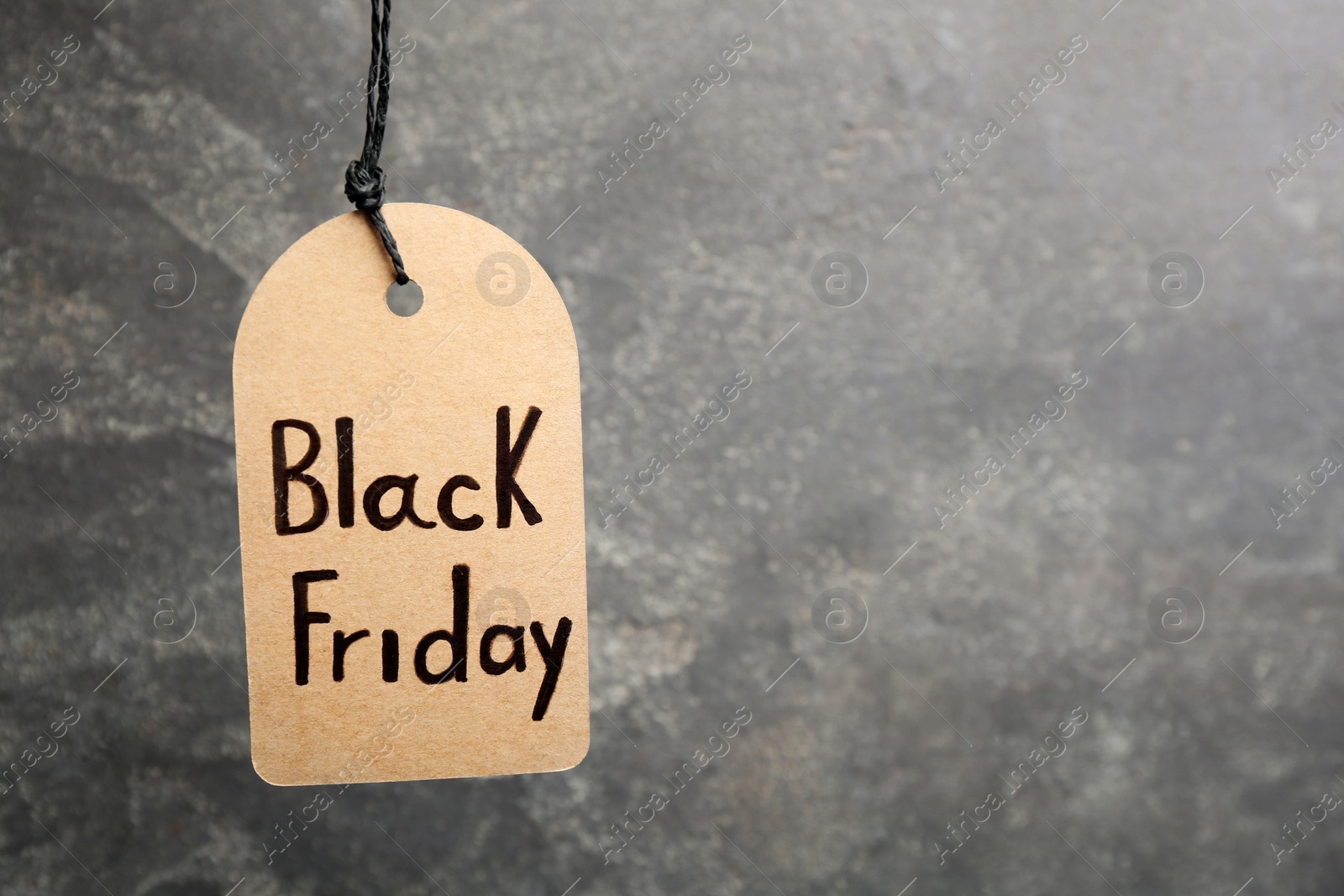 Photo of Tag with words BLACK FRIDAY hanging on grey background. Space for text