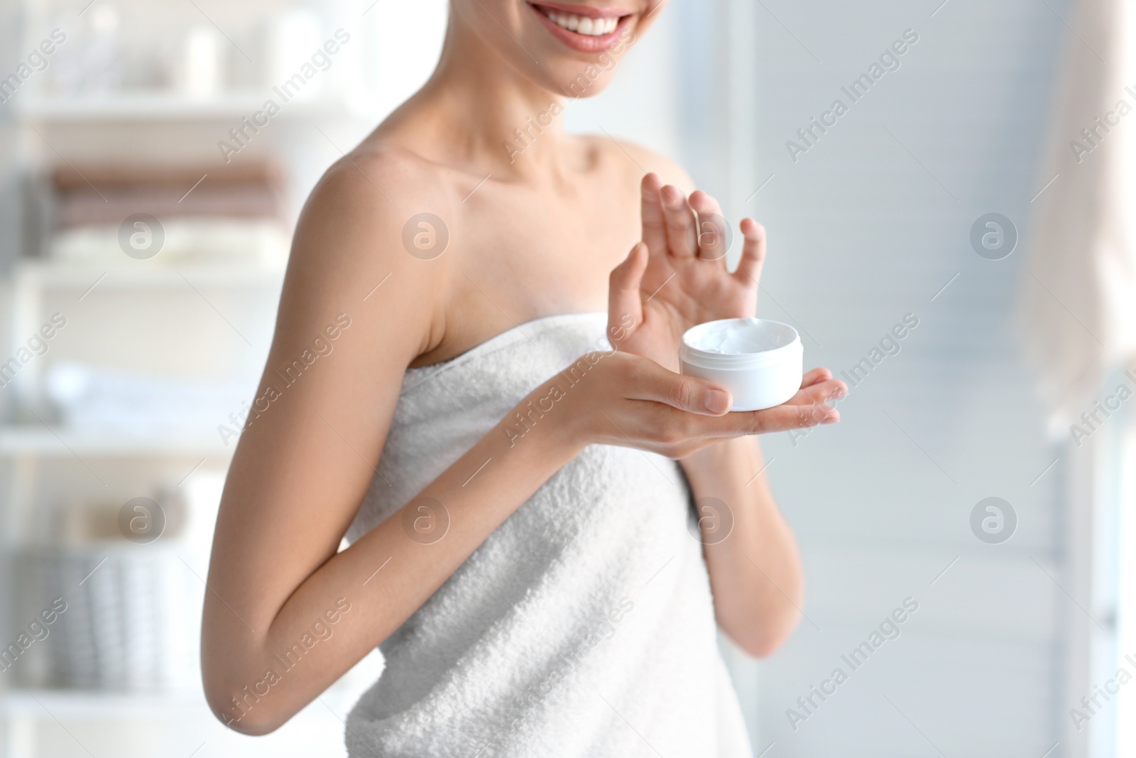 Photo of Young woman with jar of body cream at home