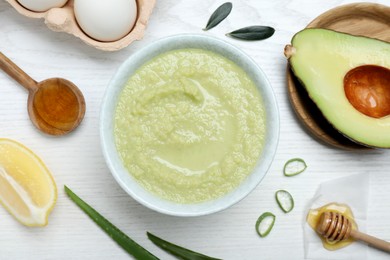 Photo of Homemade hair mask in bowl and ingredients on white wooden table, flat lay