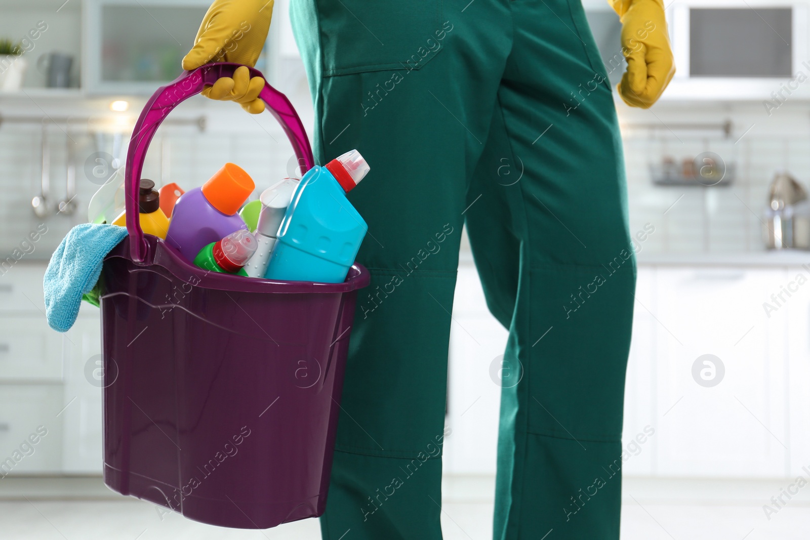 Photo of Janitor with bucket of detergents in kitchen, closeup. Cleaning service