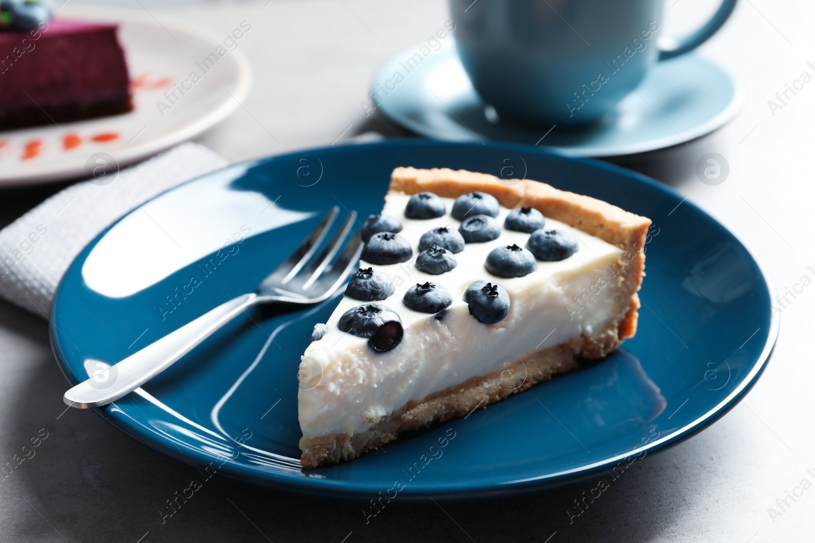 Photo of Plate with piece of tasty blueberry cake on gray table