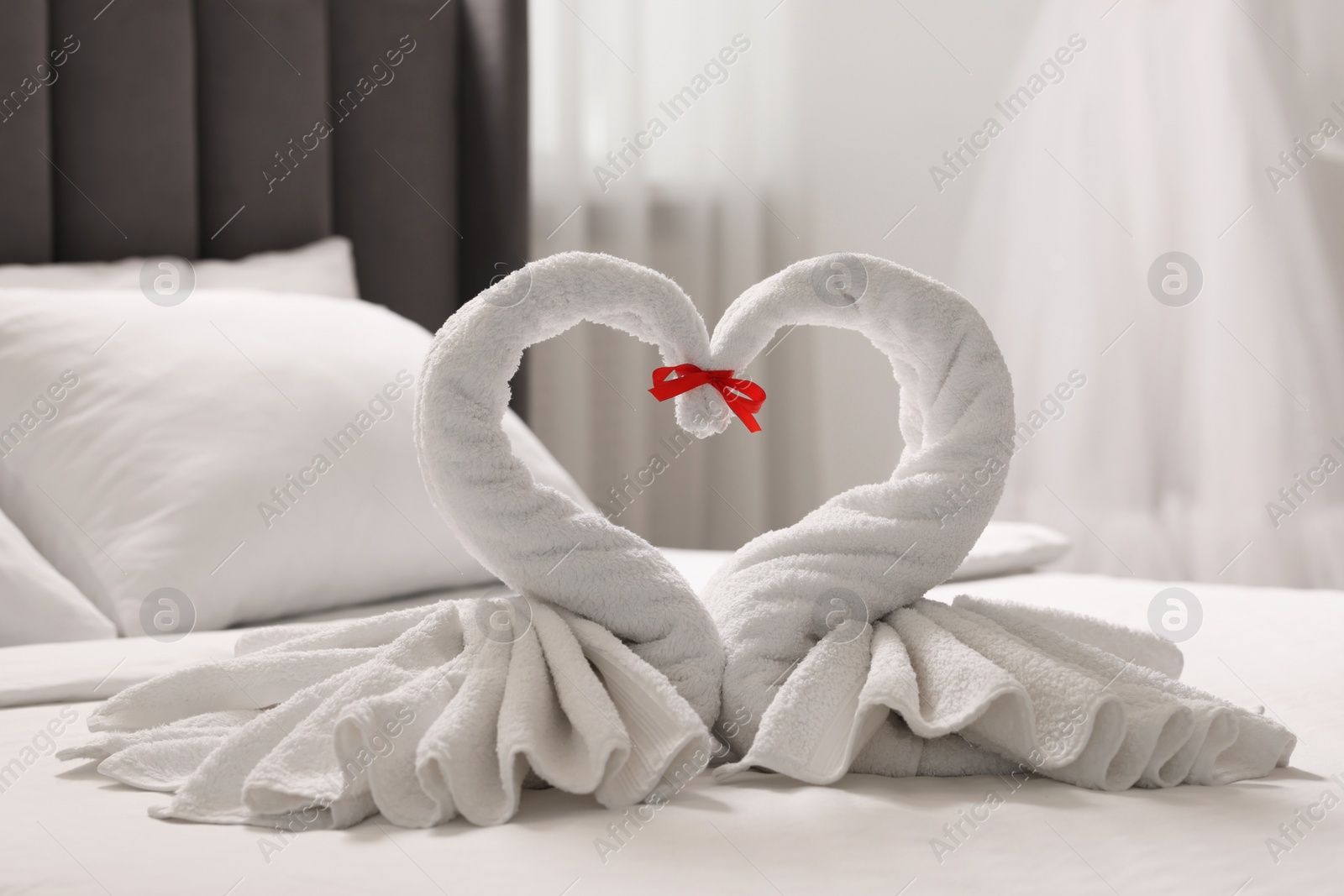 Photo of Honeymoon. Swans made of towels on bed in room