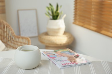 Photo of Wax air freshener with magazine on table in room, space for text. Cozy interior