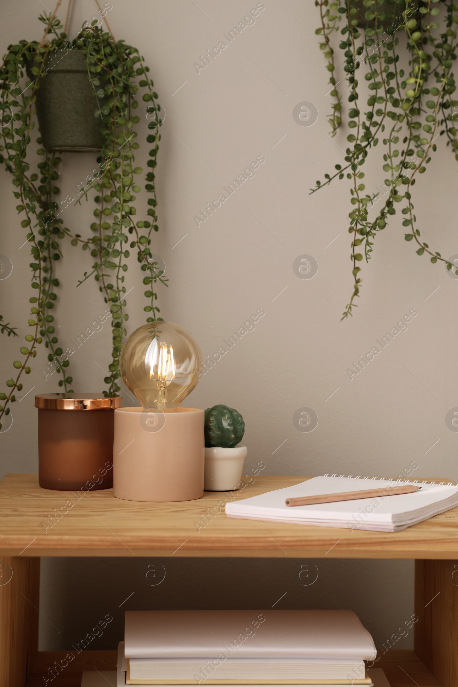 Photo of Stylish lamp and decor on wooden nightstand in room