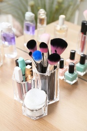 Photo of Organizer with makeup cosmetic products on wooden table near mirror