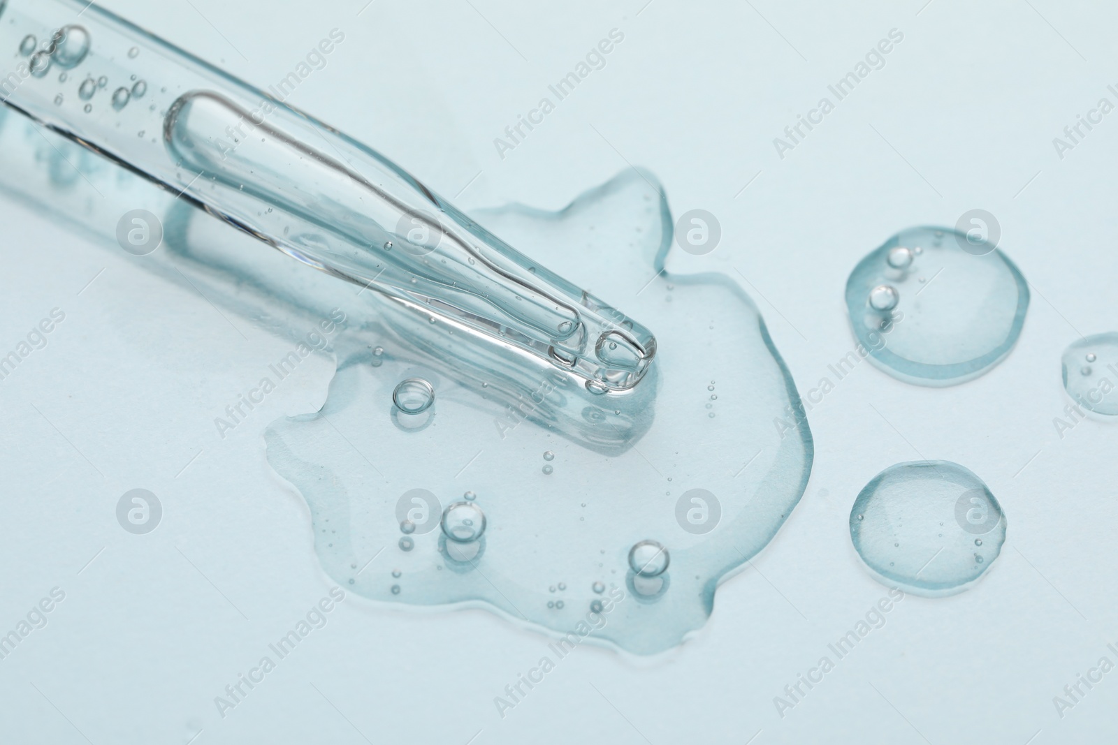 Photo of Glass pipette and transparent liquid on light background, top view