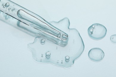 Glass pipette and transparent liquid on light background, top view