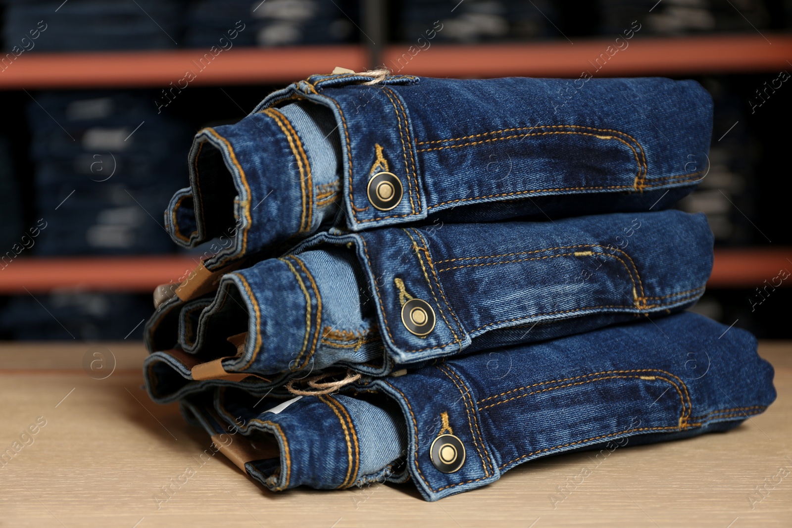 Photo of Stack of stylish jeans on display in shop