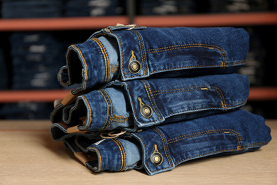 Photo of Stack of stylish jeans on display in shop