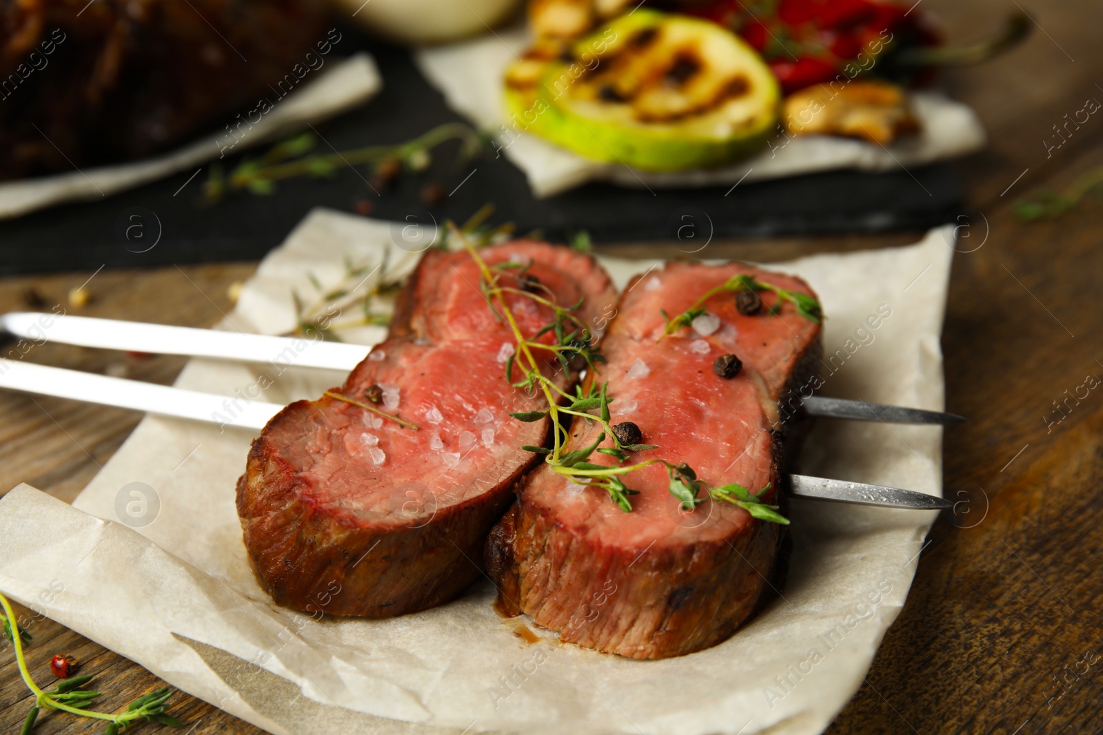 Photo of Fork with slices of grilled meat on wooden table