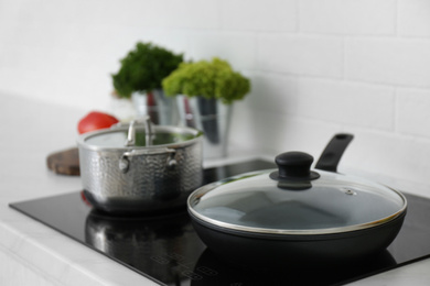 Saucepot and frying pan on induction stove in kitchen