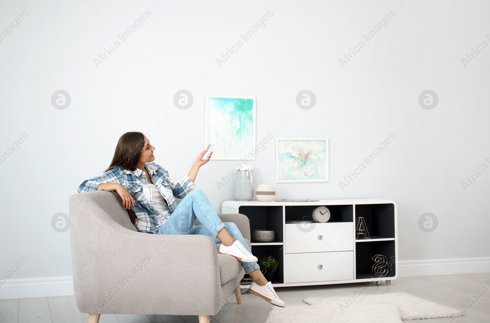 Photo of Young woman with air conditioner remote at home