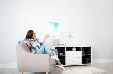 Young woman with air conditioner remote at home