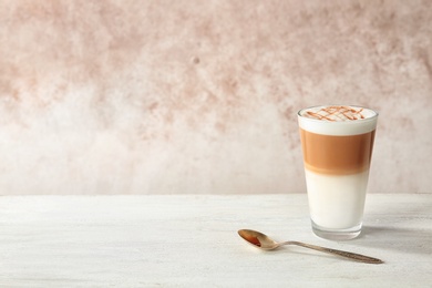 Photo of Glass of caramel macchiato on table against color background. Space for text