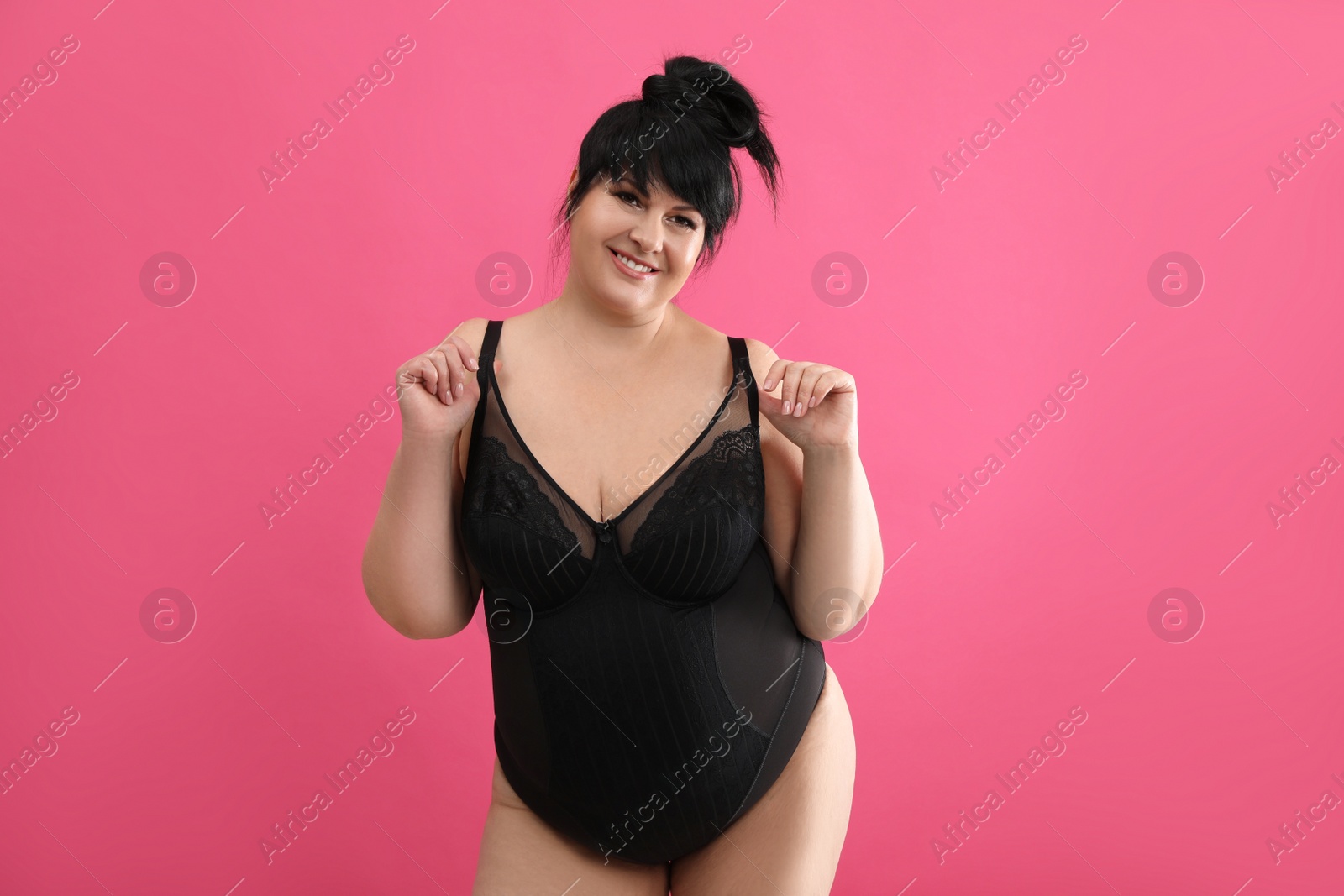 Photo of Beautiful overweight woman in black underwear on pink background. Plus-size model