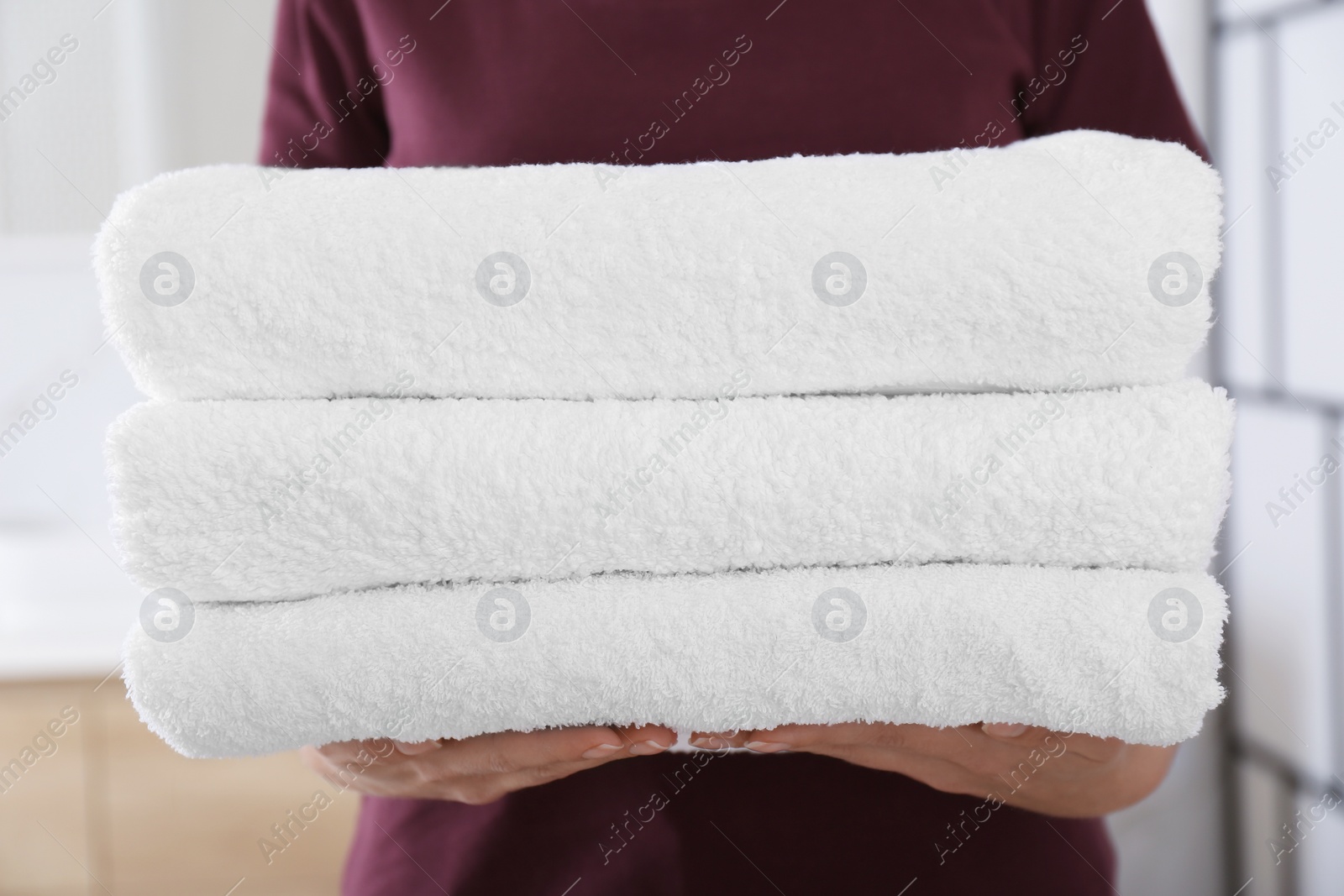 Photo of Woman holding fresh towels in bathroom, closeup