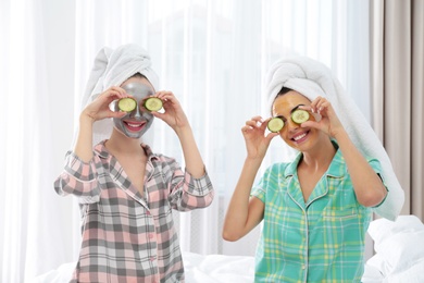 Photo of Young friends with facial masks having fun in room at pamper party