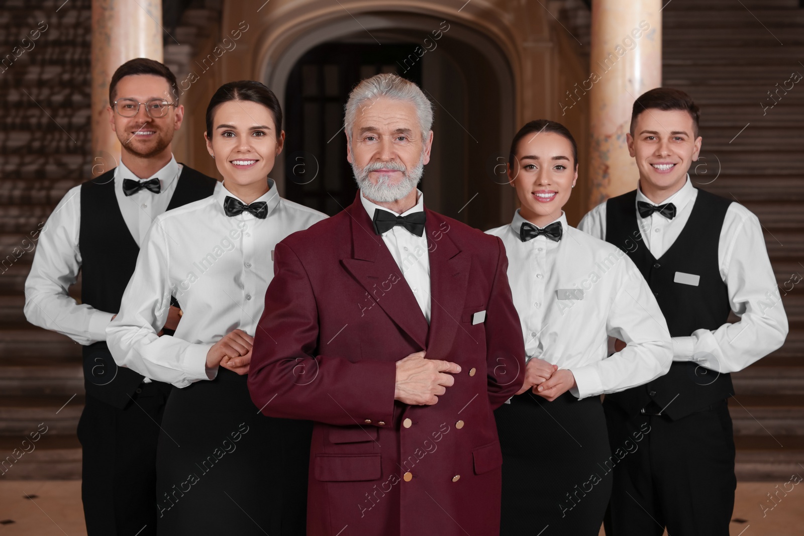 Photo of Group of young trainees with teacher in hotel. Professional butler courses