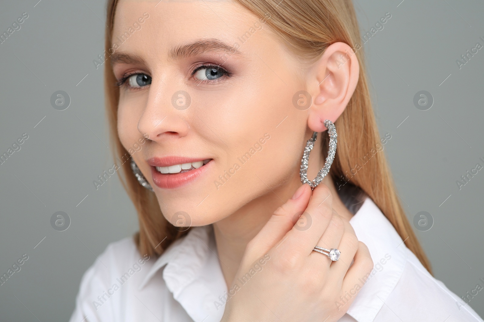 Photo of Beautiful young woman with elegant jewelry on gray background, closeup