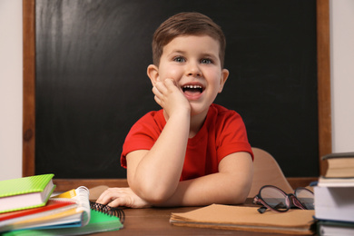 Photo of Cute little child at desk in classroom. First time at school