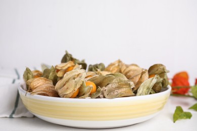 Photo of Ripe physalis fruits with dry husk on white table. Space for text