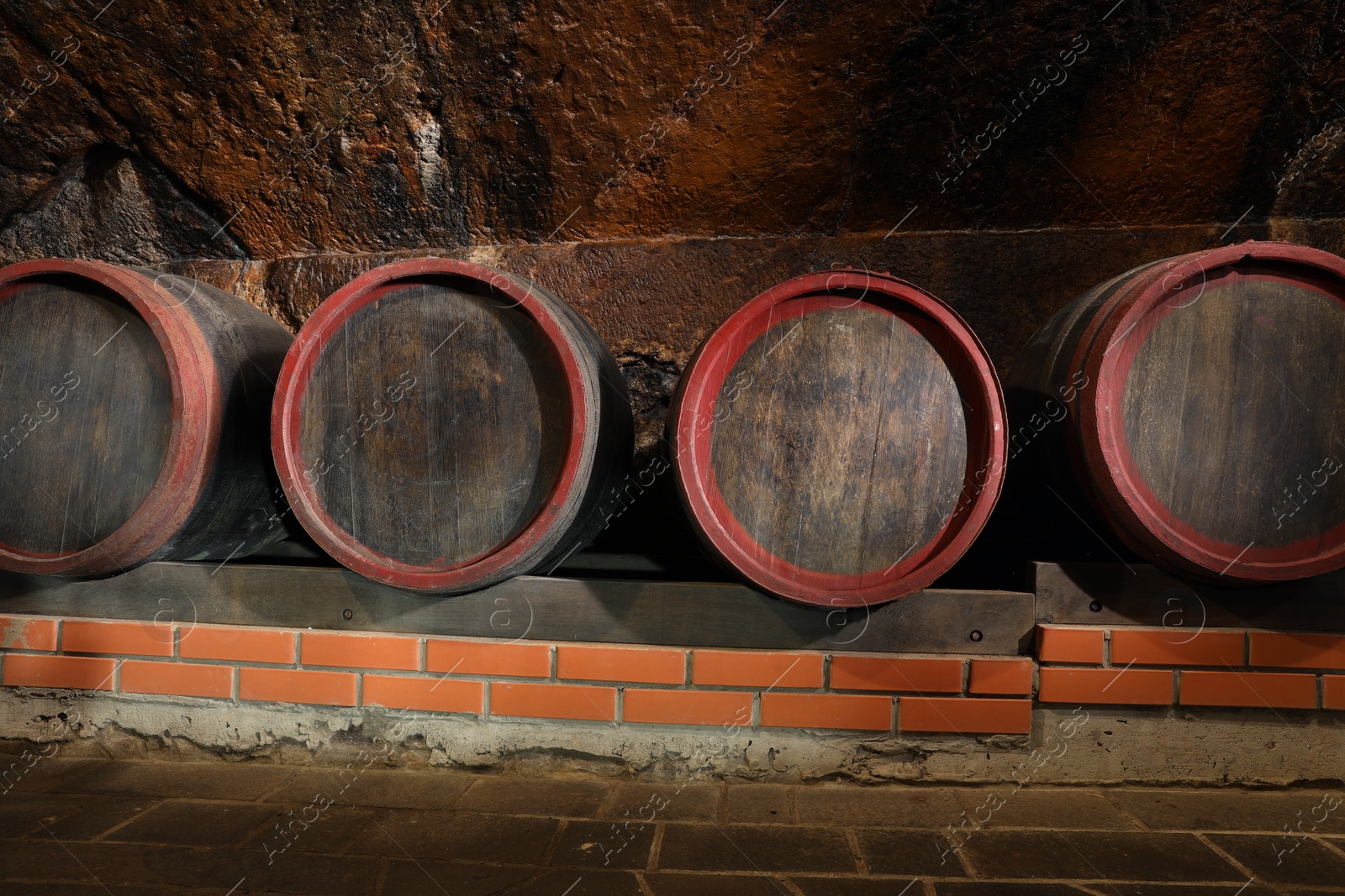 Photo of Many wooden barrels with alcohol drinks in cellar
