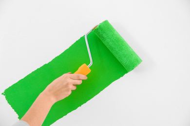 Photo of Woman painting white wall with green dye, closeup. Interior renovation