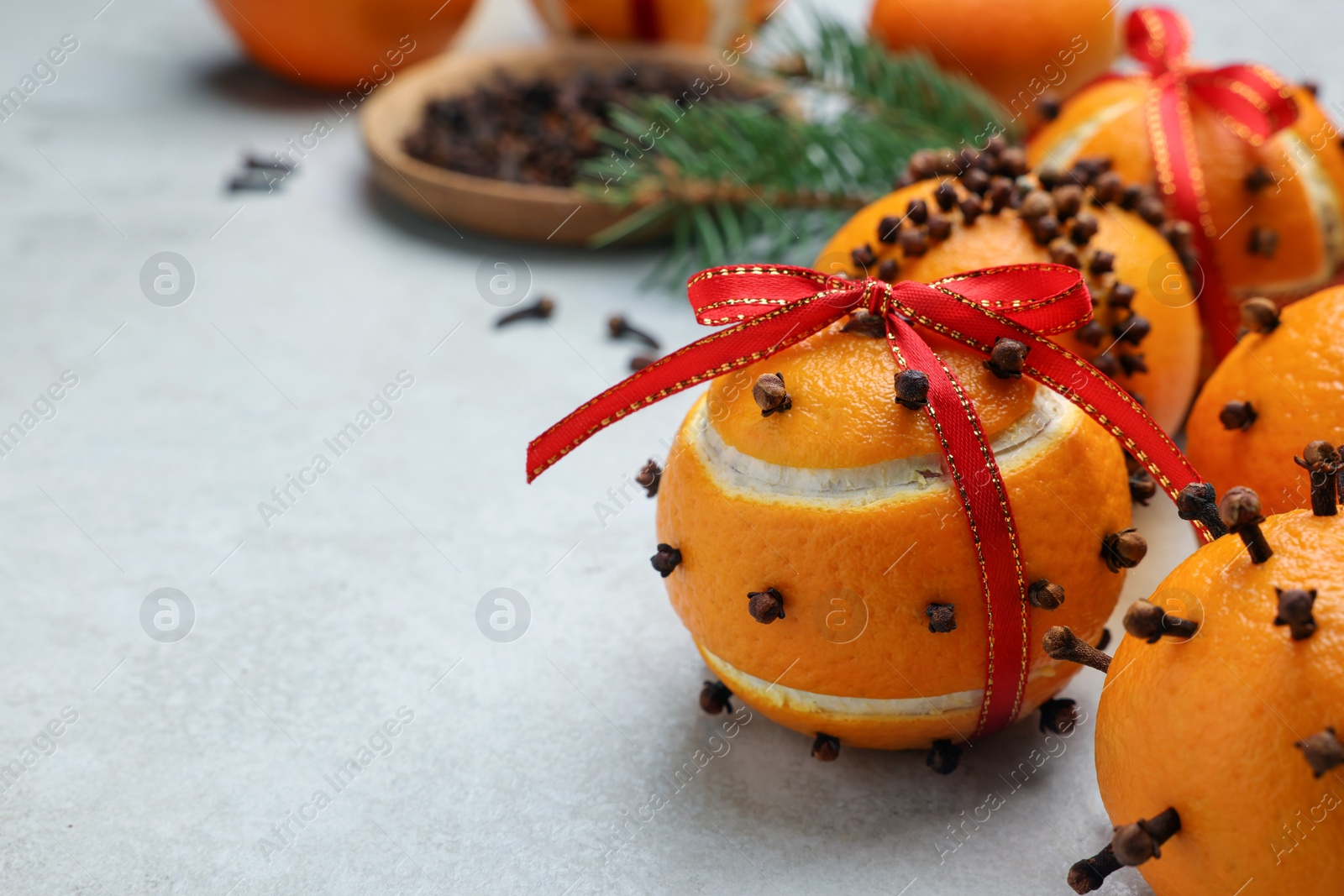 Photo of Pomander balls made of tangerines with cloves on grey table, closeup. Space for text