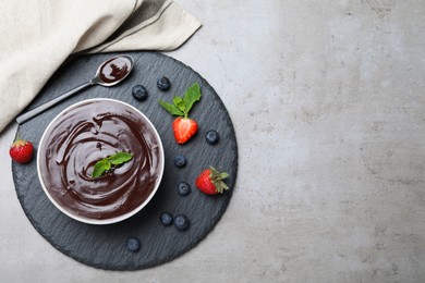 Delicious chocolate cream with berries and mint on grey table, top view. Space for text