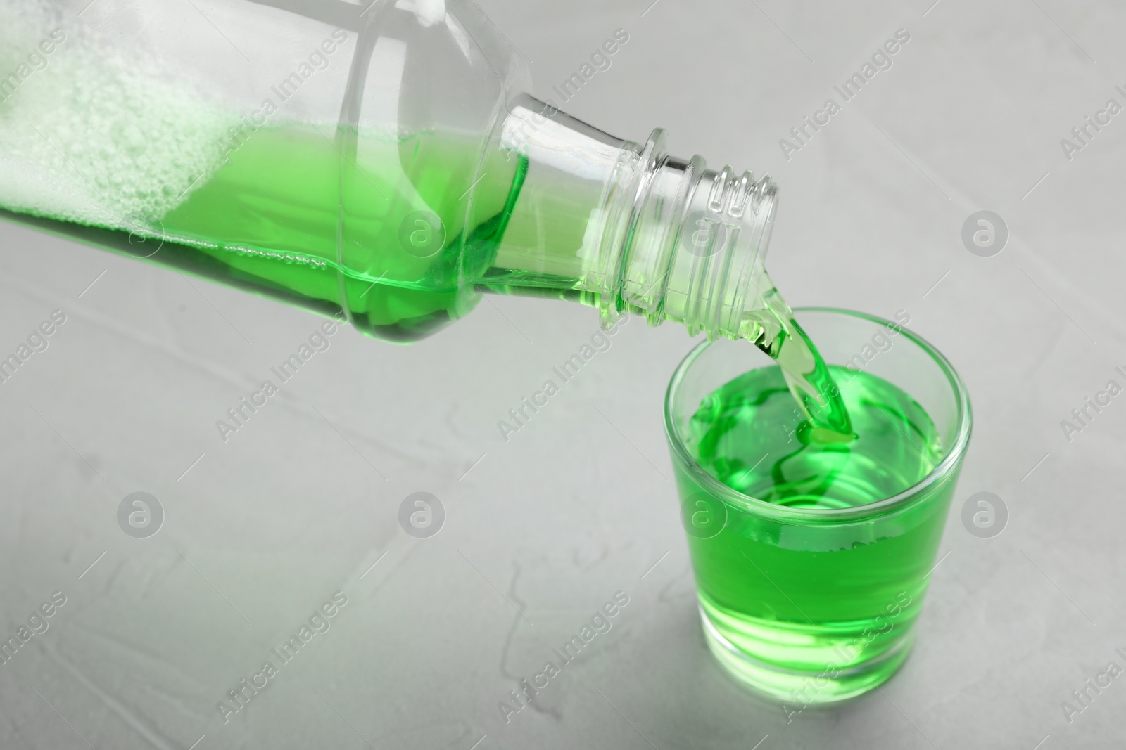 Photo of Pouring mouthwash in glass on light background. Teeth care