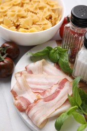 Raw pasta and fresh ingredients on white tiled table