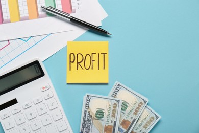 Photo of Sticky note with word Profit, diagram, banknotes and calculator on turquoise background, flat lay. Space for text