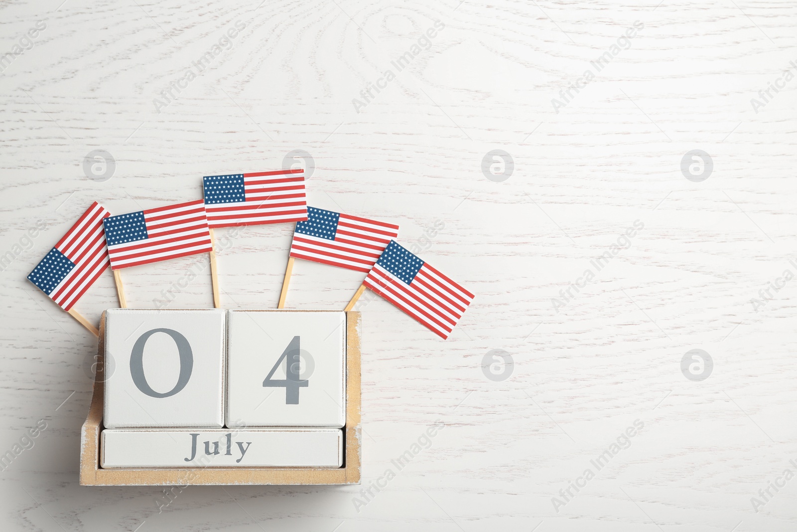 Photo of Flat lay composition with calendar and USA flags on wooden background, space for text. Happy Independence Day