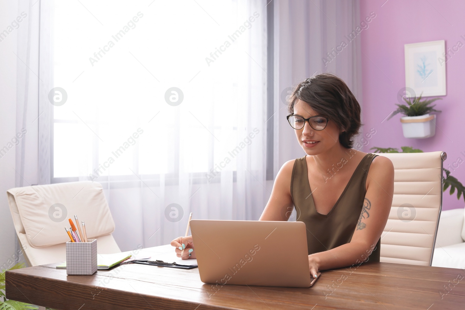 Photo of Young woman with modern laptop at desk in home office
