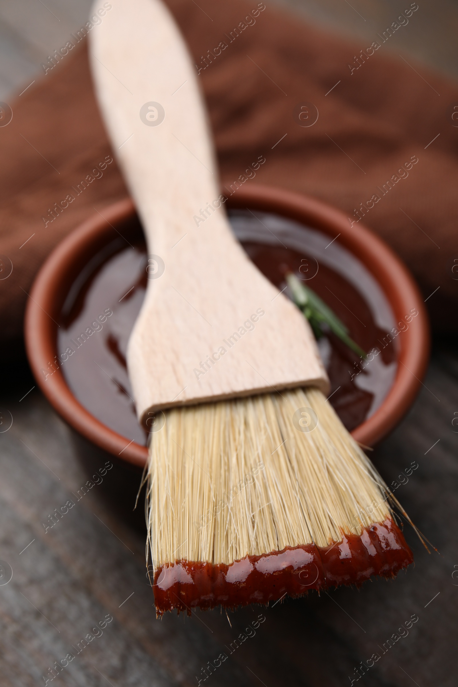 Photo of Marinade in bowl and basting brush on table, closeup