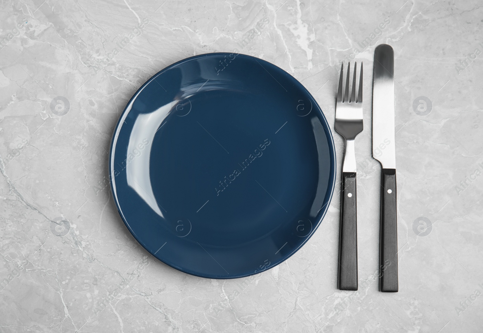 Photo of Empty blue ceramic plate and cutlery on light grey marble table, flat lay