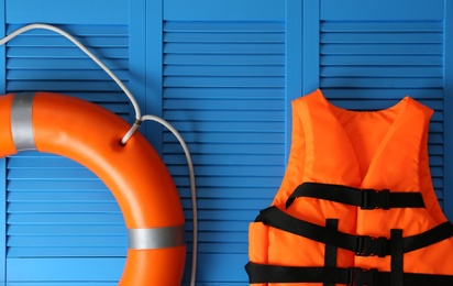 Photo of Orange life jacket and lifebuoy on blue wooden background. Rescue equipment