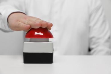 Photo of Man pressing red button of nuclear weapon at white table, closeup with space for text. War concept