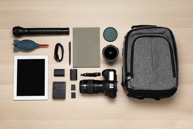 Photo of Flat lay composition with professional photography equipment and backpack on wooden table